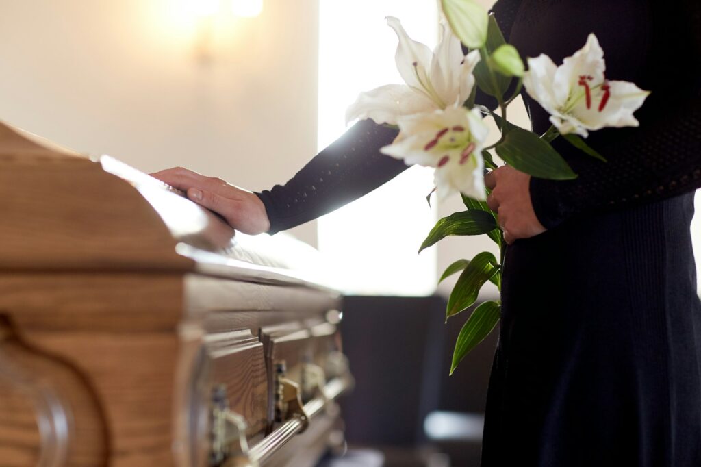 woman with lily flowers and coffin at funeral